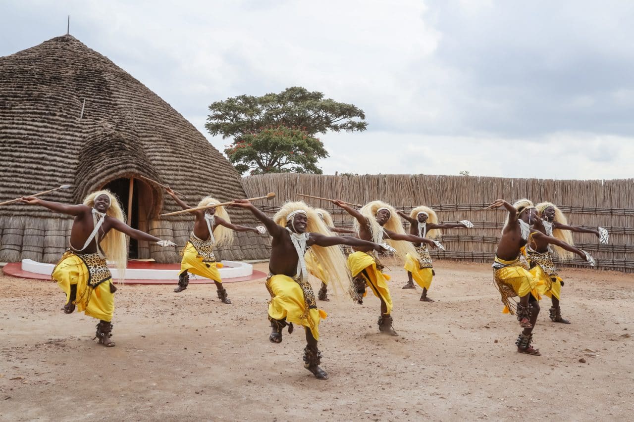 Intore dancers performing before a traditional thatched hut at the King's Palace, Nyanza